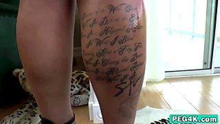 Tattooed chick shoving strap on in ass of stud